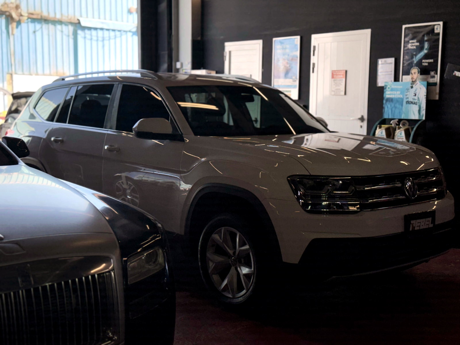 Volkswagen Atlas undergoing inspection alongside luxury cars at Rebel Motorworks Dubai