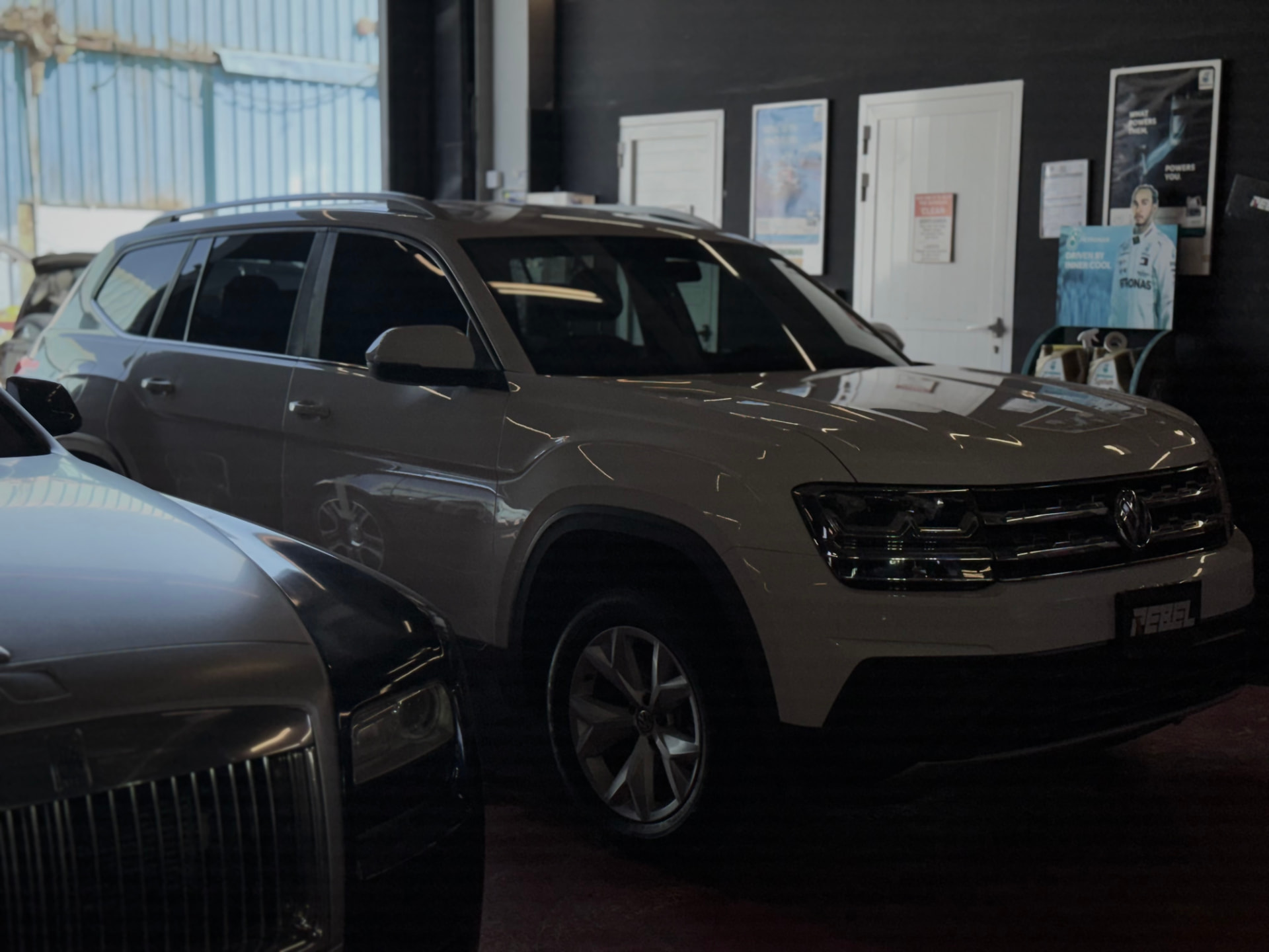 Volkswagen Atlas alongside a Rolls-Royce inside the Rebel Motorworks workshop